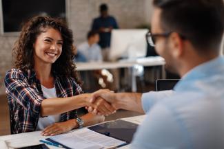 Femme signant contrat et donnant poignée de main à un gestionnaire