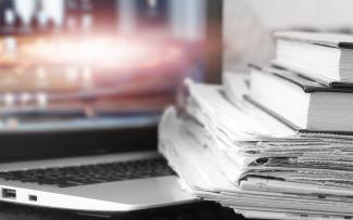 portable ouvert avec des livres et des journaux empilés sur son clavier
